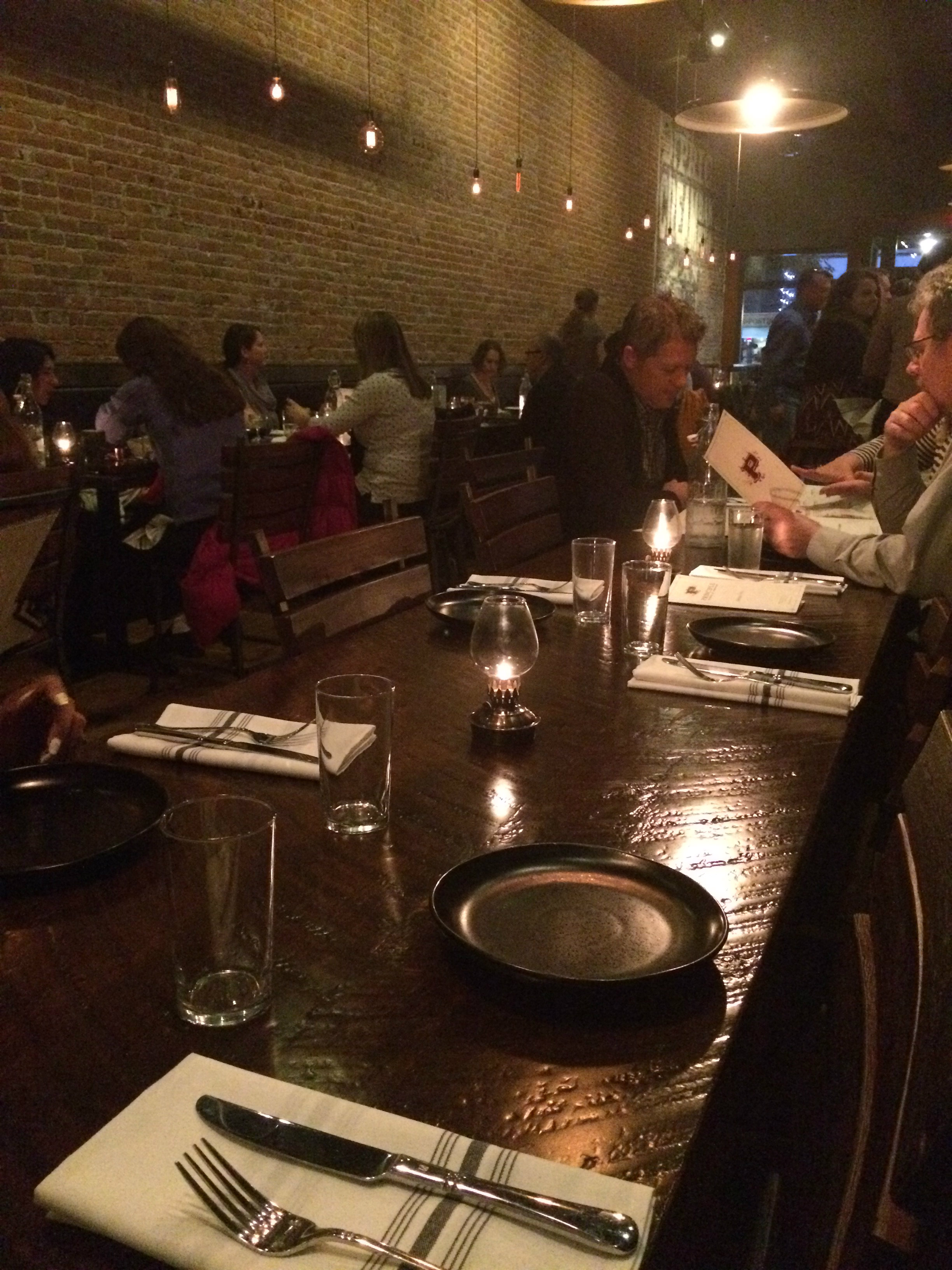 A dimly lit restaurant with a long wooden table