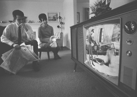 A young couple watching a black and white TV