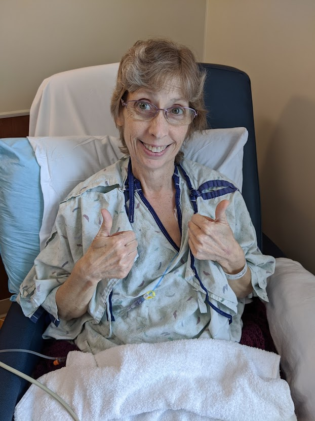 Beth Mattison in the hospital with a 
            thumbs up
