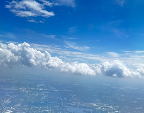 Clear blue sky with lots of fluffy white clouds over a suburban city.